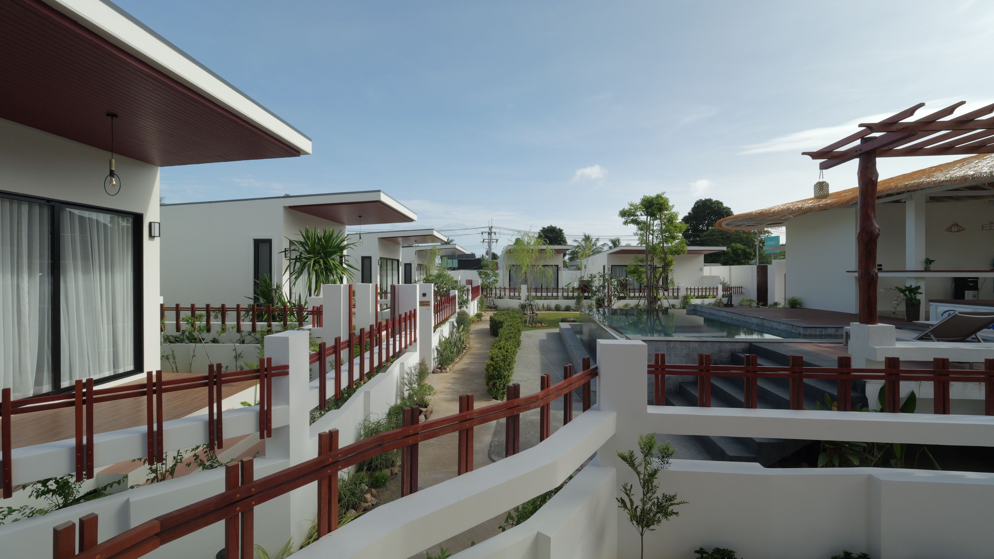 Un barrio residencial con casas modernas, cielo despejado y una piscina.