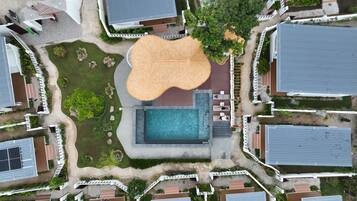 Vista aérea de una zona residencial con una piscina central, rodeada de casas de estilos arquitectónicos variados.