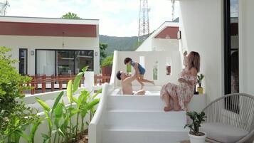 Un espacio exterior moderno con una escalera, una zona de estar y vistas a un edificio al fondo.