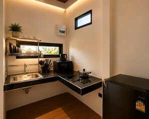 Une cuisine de taille réduite équipée d’un évier, d’une cuisinière, d’un four à micro-ondes et d’un petit réfrigérateur.