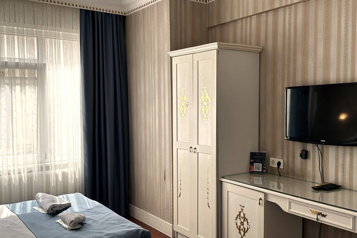 Una camera d'albergo con un letto, un armadio, una scrivania e un televisore.