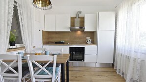 A modern kitchen with white cabinetry, a wooden countertop, and a built-in oven. - Apartment with garden and BBQ area (Umag)