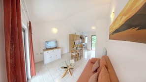 Een moderne woonkamer met een bank, een glazen salontafel en een televisie.