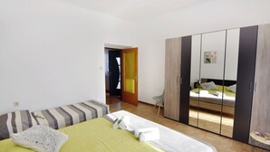 A bedroom with a bed, a wardrobe, and a door leading to another room. - Green retreat near the coast (Bašanija)
