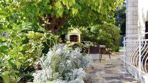 A stone patio with a wooden bench, a small wooden structure, and a white metal fence. - Green retreat near the coast (Bašanija)