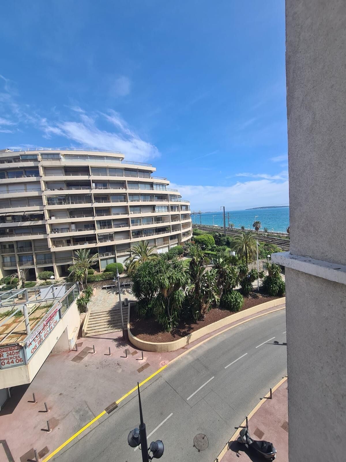 A multi-story hotel with balconies overlooking a coastal road and beach.