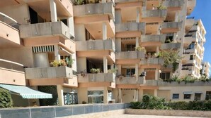 Una piscina con bordo in pietra, circondata da un edificio a più piani con balconi.