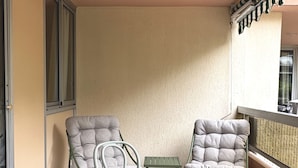 Un balcone con un tavolo, due sedie, un tavolino e un tappeto decorato.