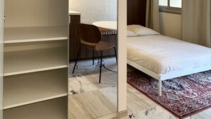 Una camera da letto con un letto, una scrivania, una sedia e un armadio.