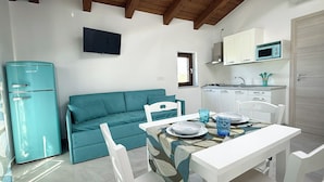 A compact kitchen with a microwave, stove, and white cabinets. - Casa Pantano - Agriturismo (Marina di Casal Velino)