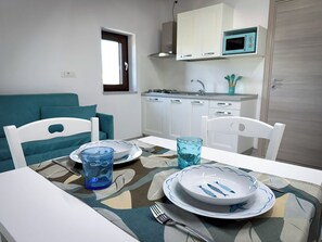 A compact kitchen with white cabinets, a microwave, and a window.