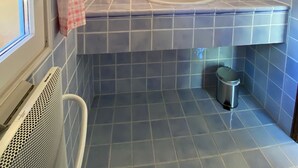 Ein Badezimmer mit zwei Waschbecken, einem Spiegel, einer Dusche und einem Mülleimer.