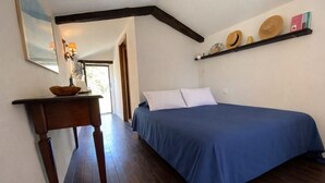 Ein Schlafzimmer mit einem Bett, einem Nachttisch, einem Spiegel und einem Regal mit Hüten.