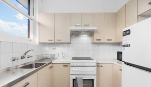 Una cocina compacta con estufa, horno, fregadero y refrigerador.