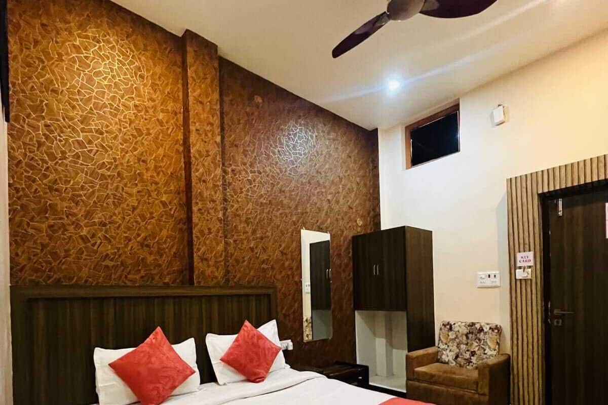 A hotel room with a large bed, a ceiling fan, a wardrobe, and a small desk with a chair.