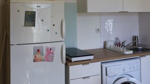 Cozinha equipada com frigorífico, máquina de lavar e pia.