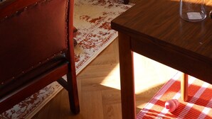 Um quarto aconchegante com sofá de madeira, mesa de jantar, laptop, luminária e estante de livros.