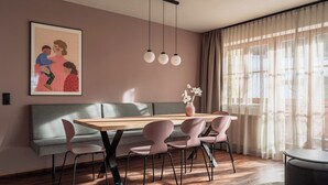 Un'area pranzo moderna con tavolo in legno, quattro sedie, una panca e una lampada a sospensione.