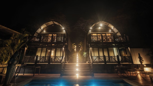 A nighttime view of a hotel with two symmetrical buildings connected by a central staircase.