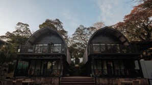Ein symmetrisches Gebäude mit Balkon, Stufen zum Eingang und einem Poolbereich.
