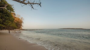 A beach with clear water, a sandy shore, and a distant landmass.