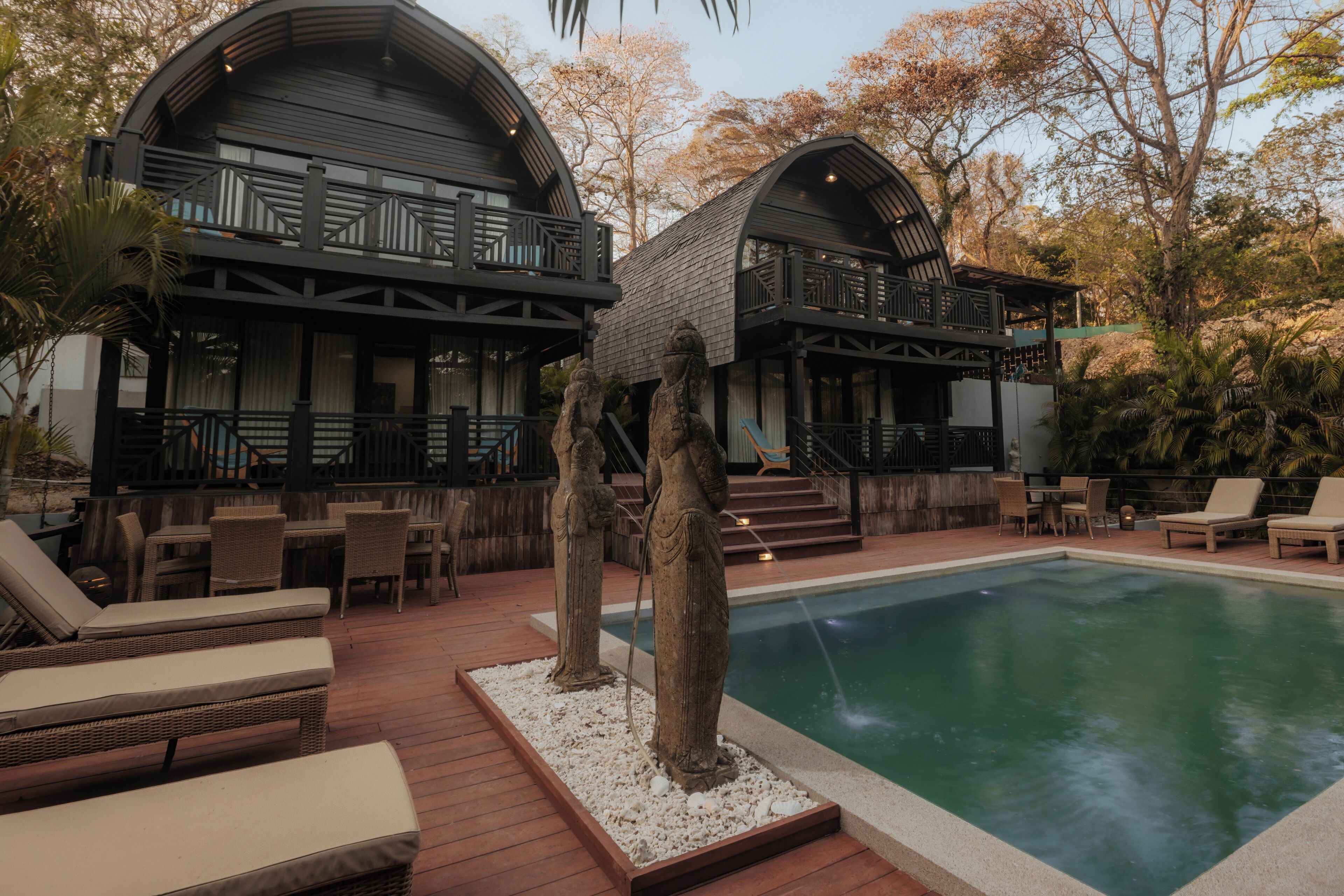 A poolside area with lounge chairs, a pool, and a building with a balcony.