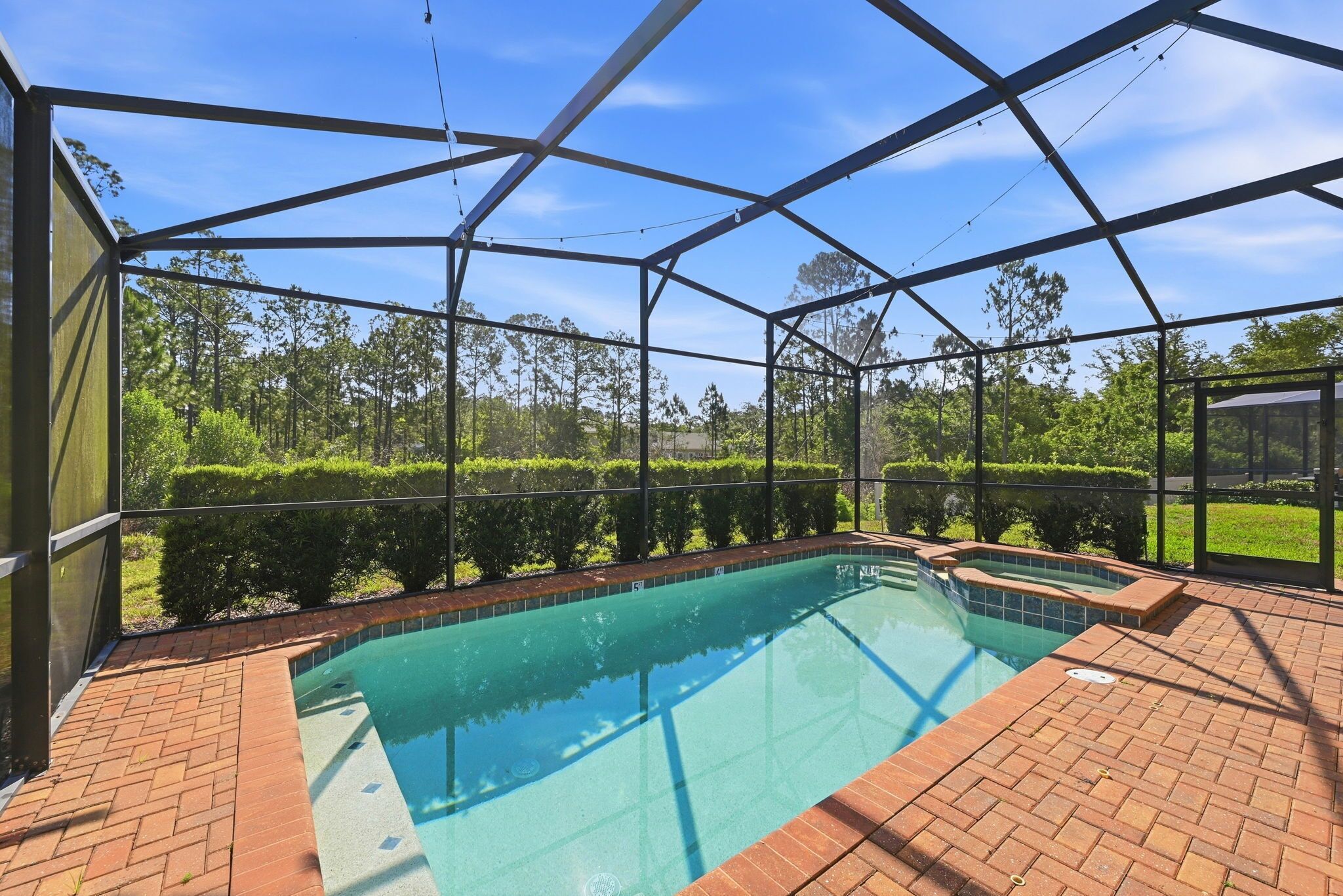 A covered outdoor swimming pool with a clear view of the surrounding greenery and trees.