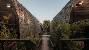 Un sentier qui mène à une piscine entourée de structures en bois et de plantes tropicales.