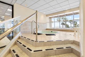 Ein Wellnessbereich mit Whirlpool, Marmorstufen und Glastrennwand.