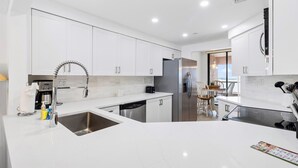 Una cocina moderna con armarios blancos, electrodomésticos de acero inoxidable y una isla grande con un lavamanos.