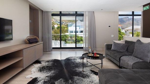 Ein modernes Hotelzimmer mit großem Fenster, einem Flachbildfernseher, einer Couch, einem Couchtisch und einem einzigartigen schwarz-weißen Teppich.