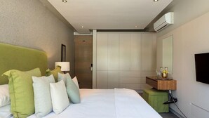 Ein Hotelzimmer mit einem großen Bett, einem Nachttisch mit Lampe, einem Spiegel und einem Fernseher.