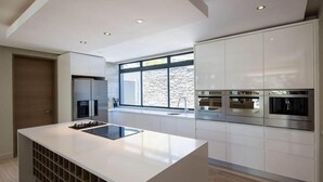 Eine moderne Küche mit Kochinsel, eingebauten Geräten und einem großen Fenster für natürliches Licht.