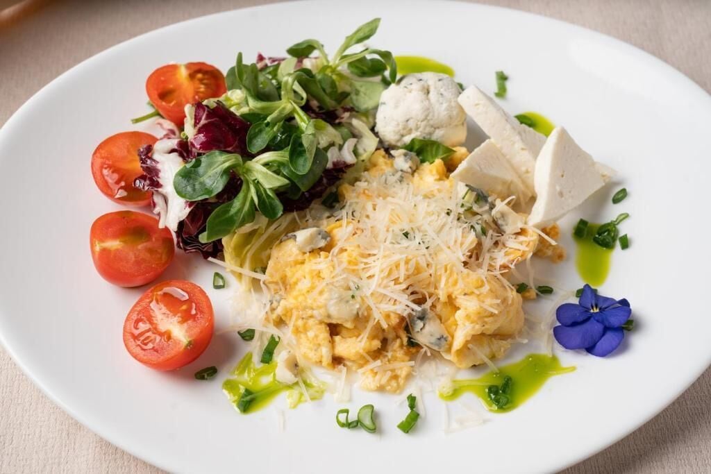 Een bord met een salade, tomaten, kaas en een bloem.