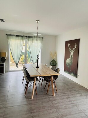 Ein Essbereich mit Holztisch und -stühlen, einer Pendelleuchte und einem Hirschgemälde an der Wand.