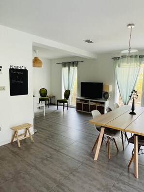 Ein modernes Wohnzimmer mit Essbereich, einem Fernseher und einem Kreidetafel-Schild.