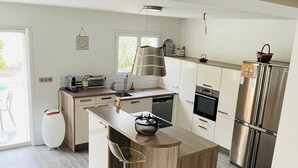 A modern kitchen with a central island, stainless steel appliances, and a view of the outdoors. - Private villa with pool and garden (Ollioules)