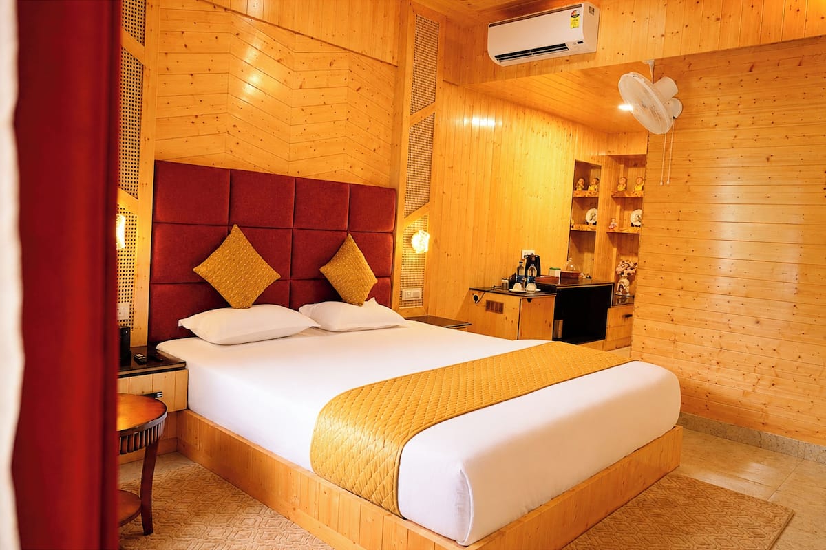 Una habitación con paneles de madera, una cama, una mesita de noche y un pequeño escritorio con una silla.