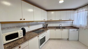 A kitchen with white cabinets, a microwave, a stove, a sink, and a dishwasher.