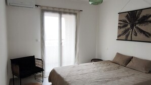 Un dormitorio con cama, escritorio, silla, lámpara colgante e imagen en la pared.
