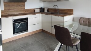 Una cocina moderna con horno empotrado, cafetera y televisor de pantalla plana sobre la encimera.