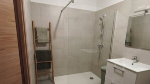 Un baño moderno con ducha, lavabo y espejo.