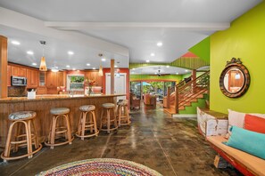 Eine geräumige Küche mit Barbereich, einer Treppe und einem farbenfrohen Teppich.