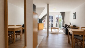 A modern interior with a dining area, a sofa, and a balcony with a railing. - Vacation apartment no. 14 in Neddesitz (Neddesitz)