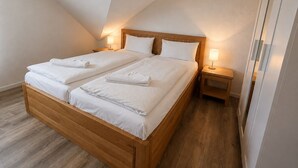 A double bed with wooden headboard, two bedside tables, and a nightstand. - Vacation apartment no. 14 in Neddesitz (Neddesitz)