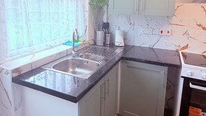 A kitchen with a double sink, a stove, and a window with frosted glass. - House In Cannock-3 Bed Sleeps 5 (Cannock)