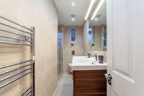 Ein modernes Badezimmer mit Glasdusche, einem Doppelwaschtisch und einem Handtuchhalter.