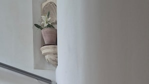 Una escalera con barandilla, una planta en maceta y un muro de piedra.