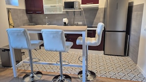 Una cocina moderna con una isla central, taburetes de bar, un refrigerador y un microondas.