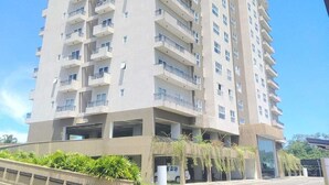 A multi-story residential building with balconies, a parking garage, and a curved road in front. - Elegant 3BR Apartment Near Galle Fort & Beach (Galle)